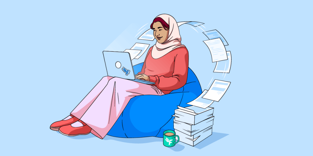 A lady sitting on a bean bag and working on a laptop