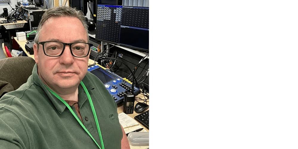 Mark Ninnim sat at a desk with a monitor and lighting equipment behind him.